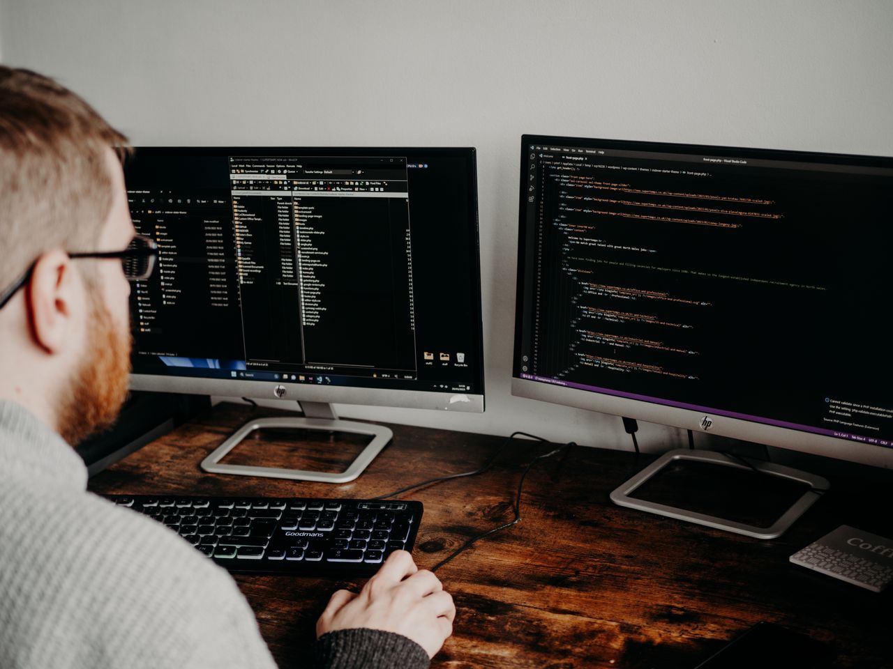 Services Software developer working on code with dual monitors in a home office setting.