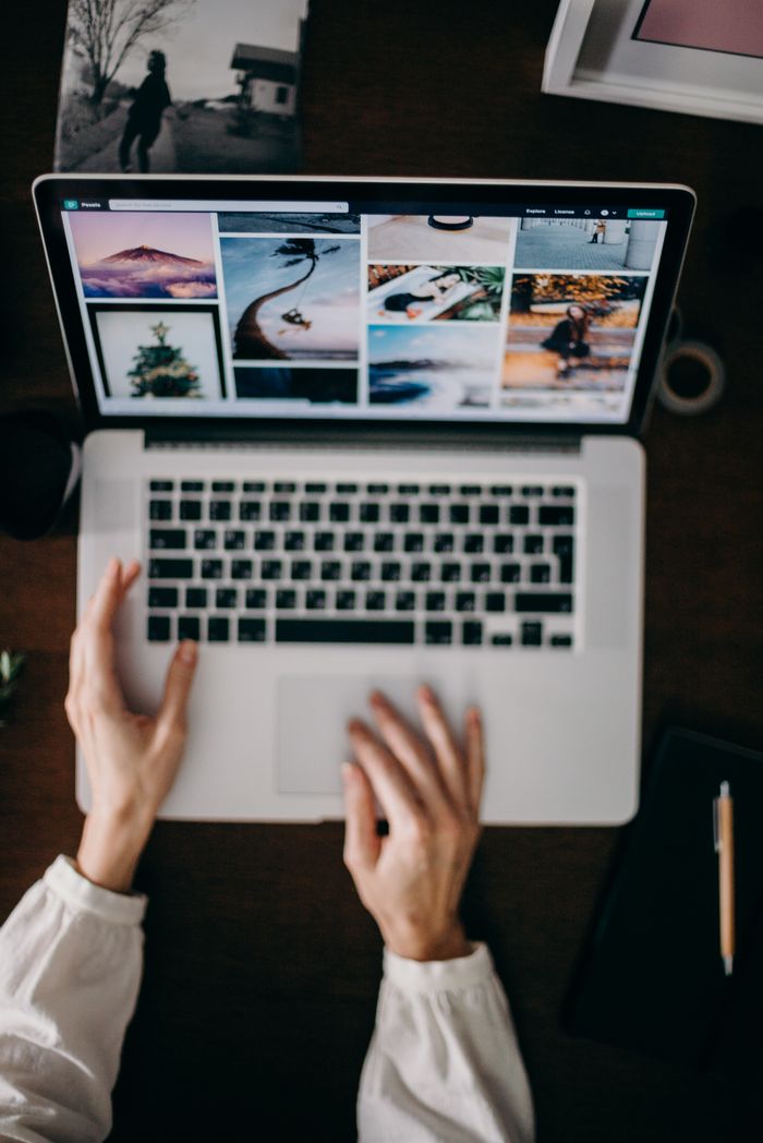 About Hands using a laptop to browse photo galleries, illustrating digital creativity and remote work.